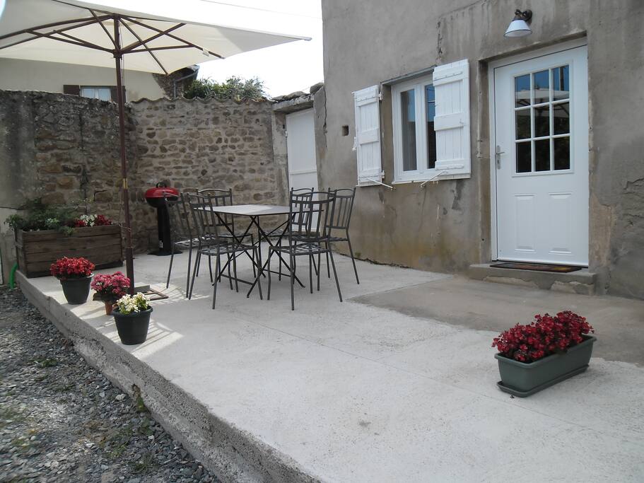 Terrasse fleurie avec salon de jardin , parasol et barbecue