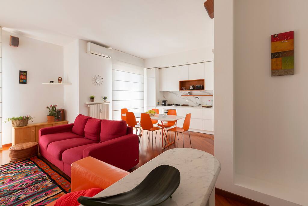 The living room zone: sofa bed x2, AC, TV & the equipped kitchen and the dining table