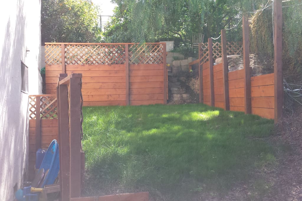 Private backyard with patio for BBQ, grass for playing, and shade for hot days.