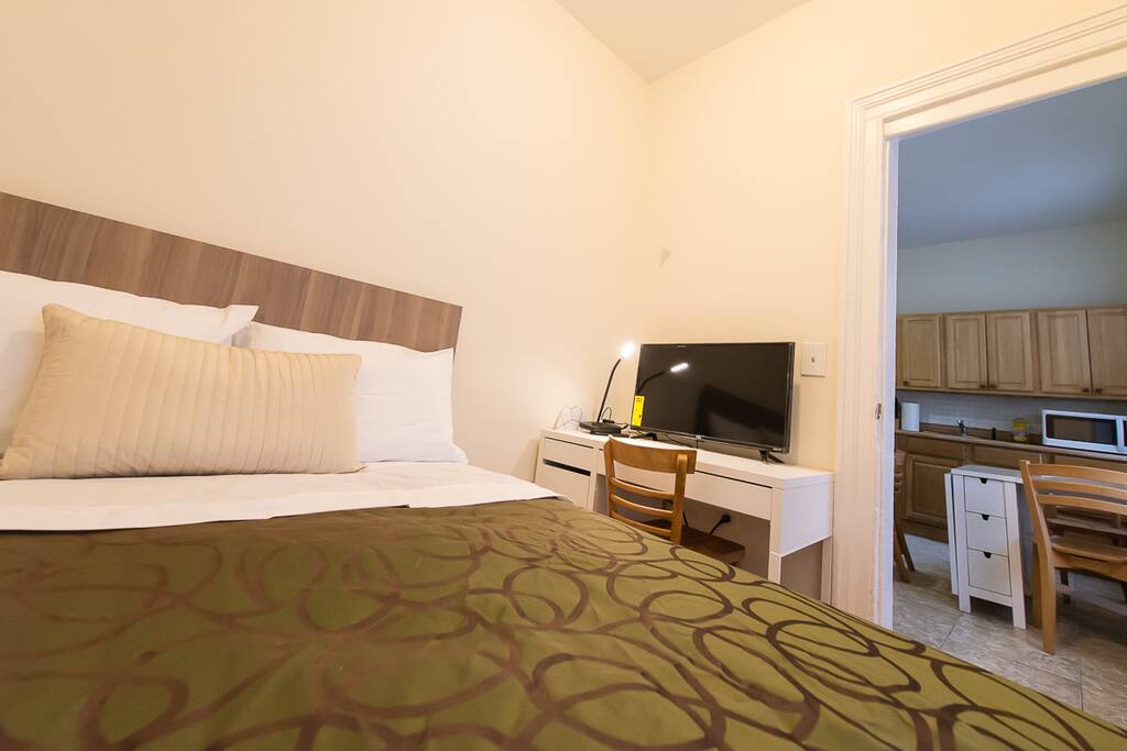 Bedroom with desk and TV. Kitchen is outside of the bedroom
