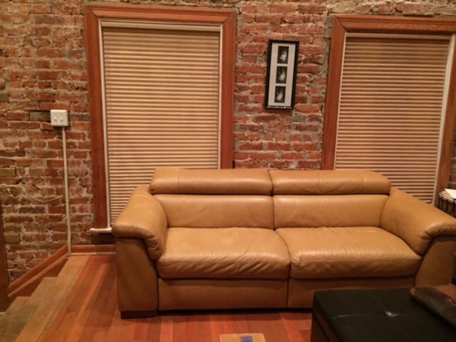 Modern living room with exposed brick walls and double automated reclining leather couch
