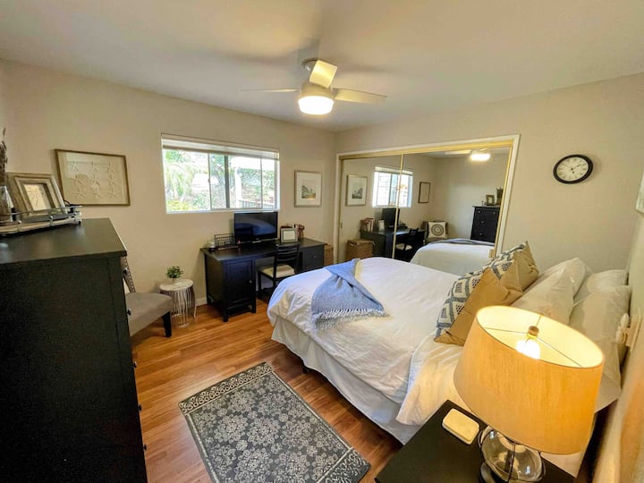 ห้องนอนในโถงทางเดินพร้อมเตียงควีนไซส์โต๊ะทำงานเก้าอี้ตู้เสื้อผ้าและตู้เสื้อผ้าขนาดใหญ่