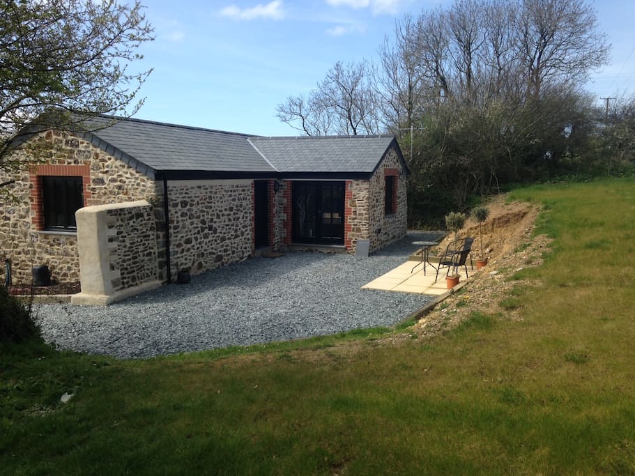 Parking area, entrance and patio on the right hand side. Large private garden backing onto farmland and goats!