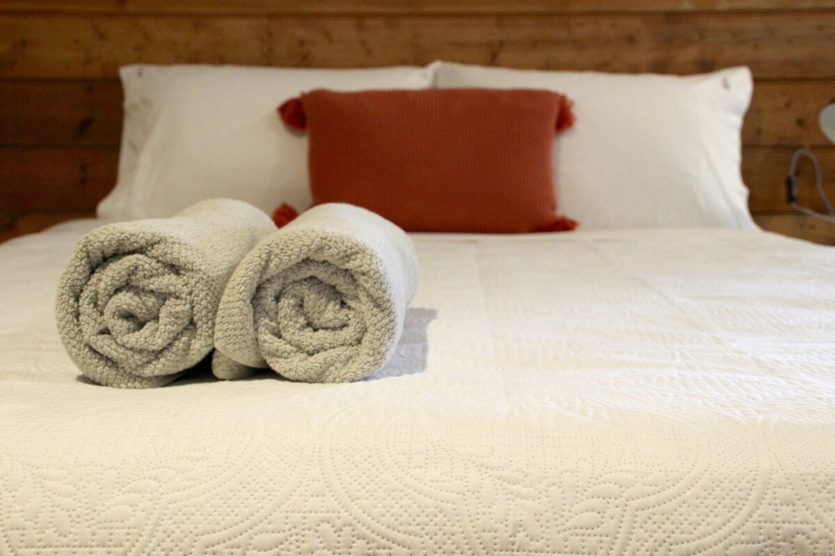 Cama tamaño queen en el entorno del estudio, toallas de calidad y ropa de cama para que tu estancia sea agradable.