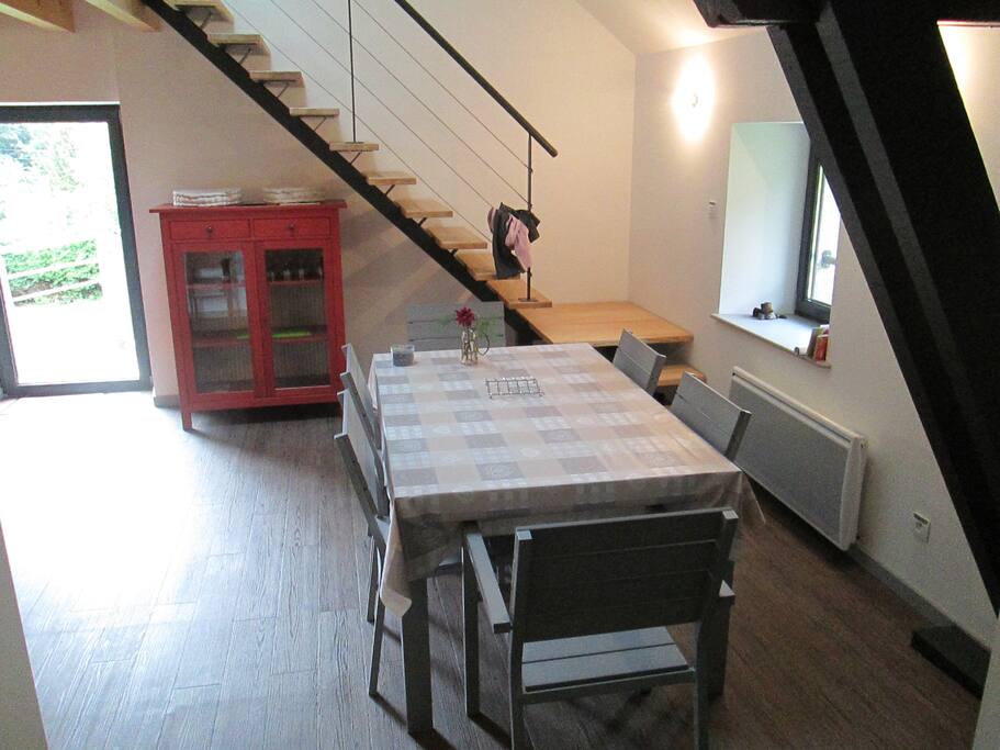 Aperçu du séjour avec l'escalier montant à l'étage, et à gauche, porte-fenêtre pour l'accès à la terrasse.