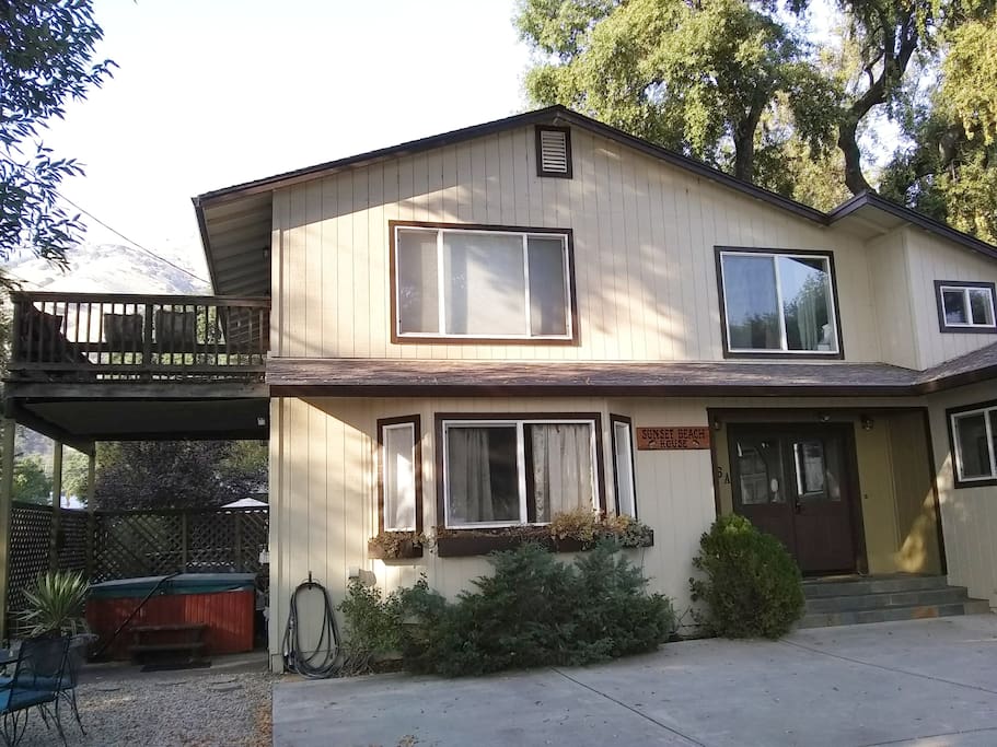 Front of sunset beach house with hot tub on left and deck facing lake.