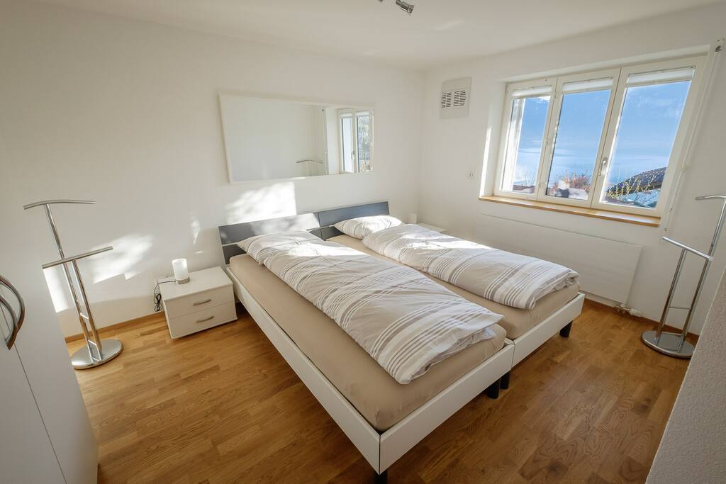 Helles Schlafzimmer mit 2 Betten, 1 Kinderbettchen und mit grossem Kleiderschrank.