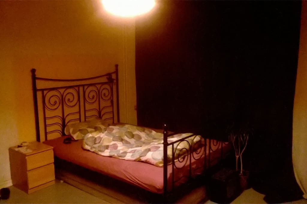 Doppelbett, Die Vorhänge sind blickdicht, Die Wand ist sandfarbend-terrakotta.