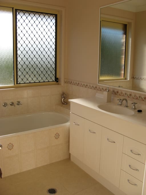 Bright, fully equipped private bathroom with bath and shower. Separate toilet adjacent.