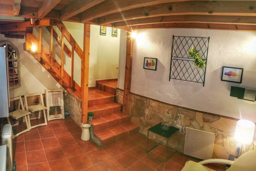 Desde el salón puedes acceder al dormitorio subiendo las escaleras de madera.
