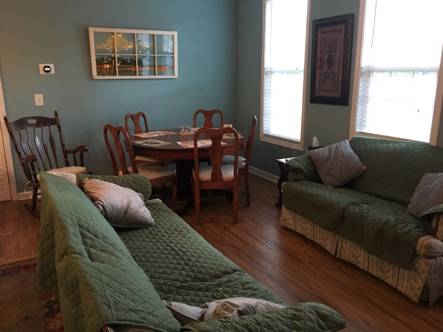 Living room and dining room, featuring pet-friendly washable couch covers and a large antique dining table. Extra inserts for the table are available to accommodate large parties.