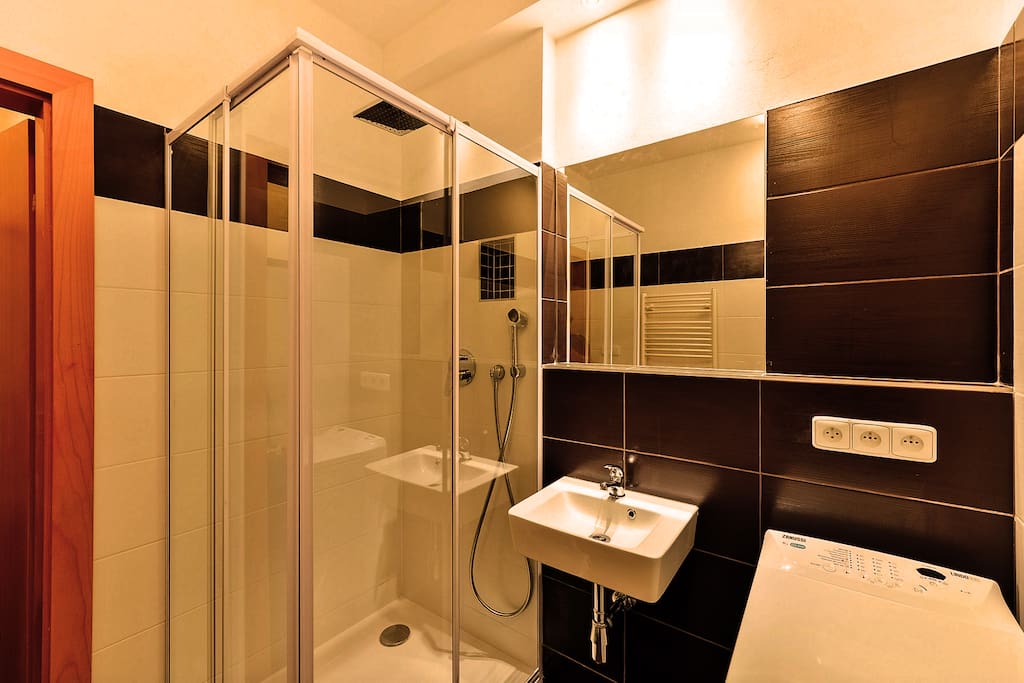 The bathroom has a shower cabinet, washing machine, wash basin, and a toilet seat.