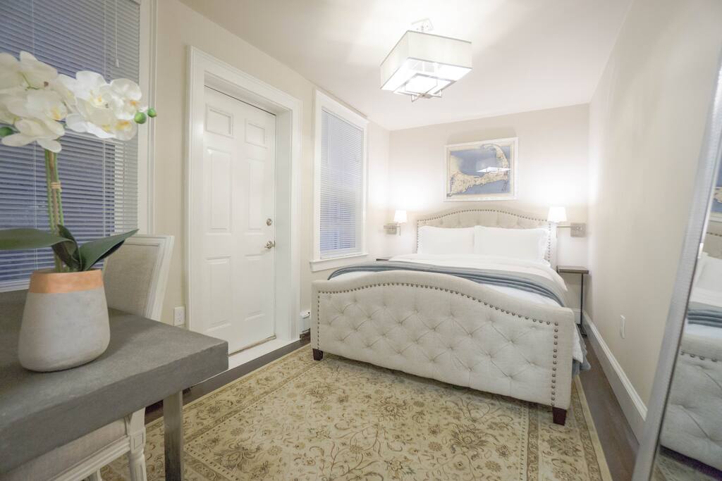 Bedroom features a queen size bed, two night stands, a small desk and chair, and a closet