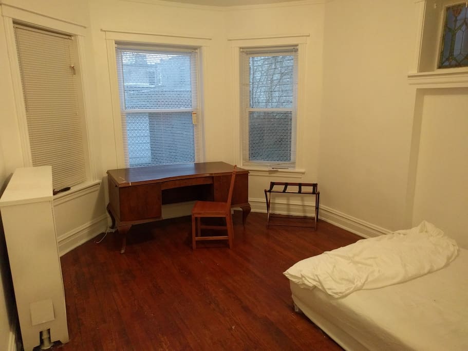 Rear bedroom (yours) with large desk, thick queen mattress, luggage rack.
