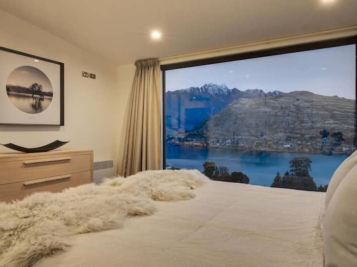 Master bedroom with unobstructed lake and mountain views through the floor to ceiling window.