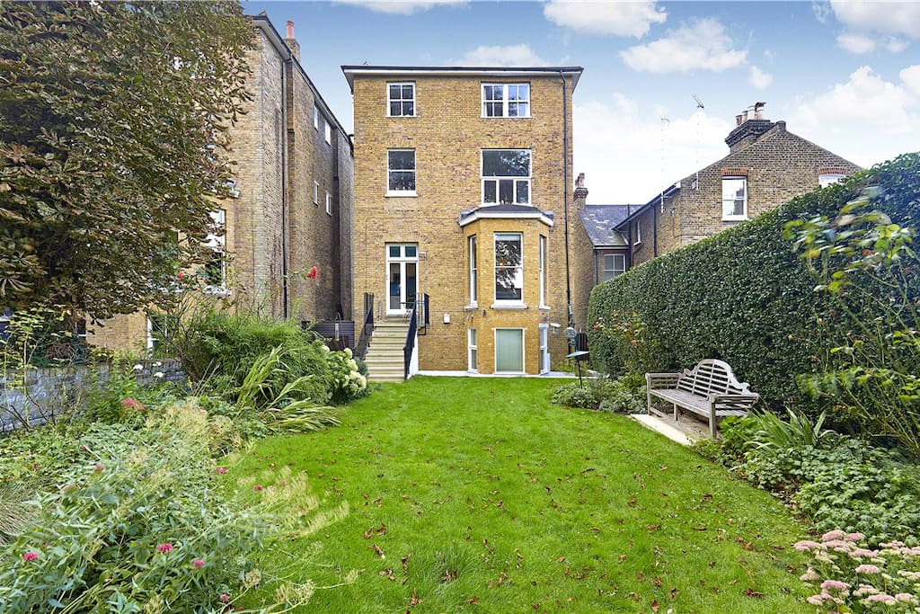 Balcony with table and chairs, stairs leading down to private garden, opening onto large communal garden