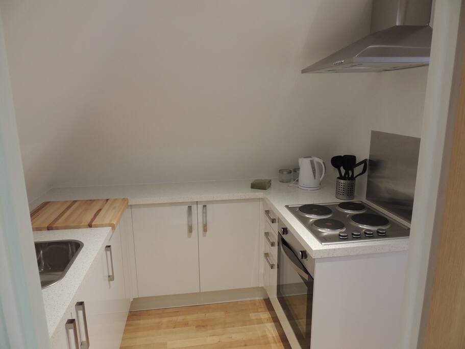 Kitchen with cooker, fridge, washing machine.