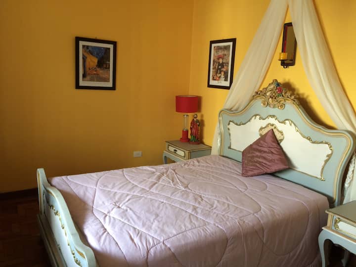 Ოთახი ორადგილიანი საწოლით, კარადებითა და სამუშაო სკამით.