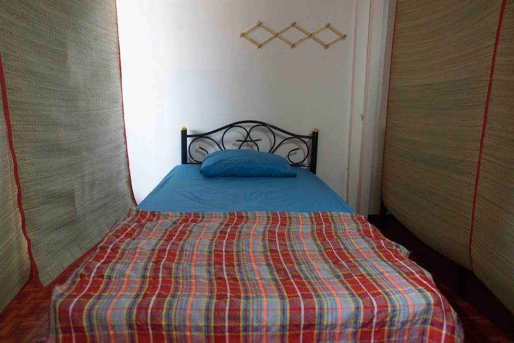 Single bed at dorm room with the bamboo curtain.