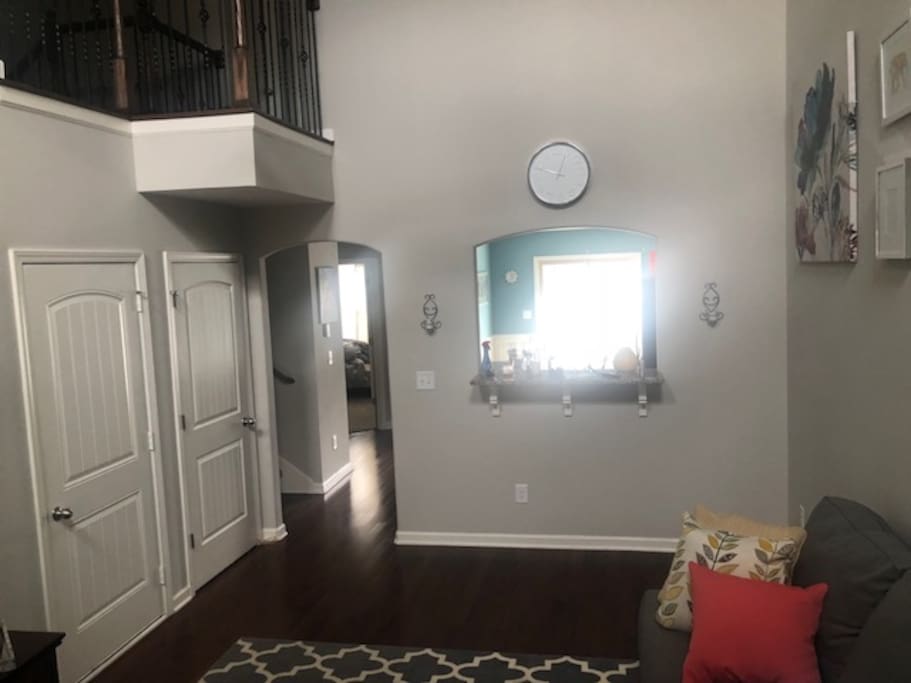 Living space has 55" mounted television, grey sectional and an overlook. Plenty of space for gathering.