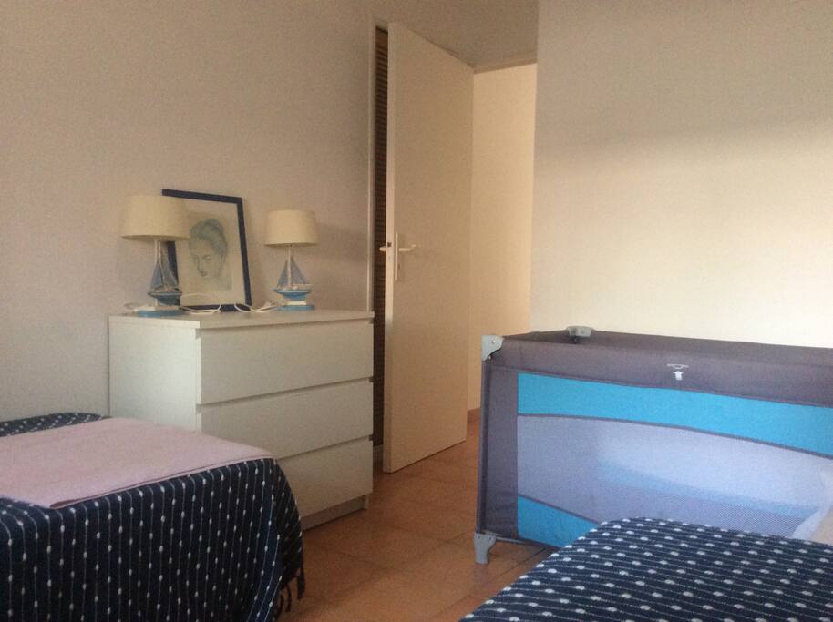Chambre avec deux lits simples (possibilité de les rapprocher), un lit parapluie (si besoin). Un placard penderie et une commode.
Fenêtre côté rue. Le bâtiment est séparé de la rue par la cour d'entree principale. Double vitrage et volets à toutes les fenêtres de l'appartement.