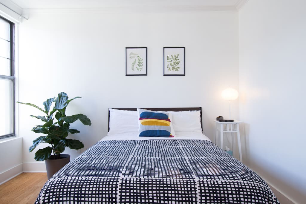 Large master bedroom with full-sized bed and two east-facing windows