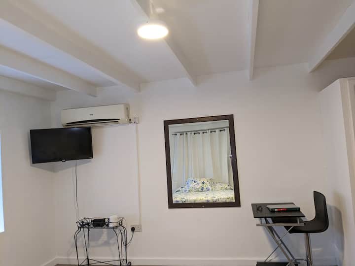 Dormitorio con televisión, aire acondicionado y escritorio.
