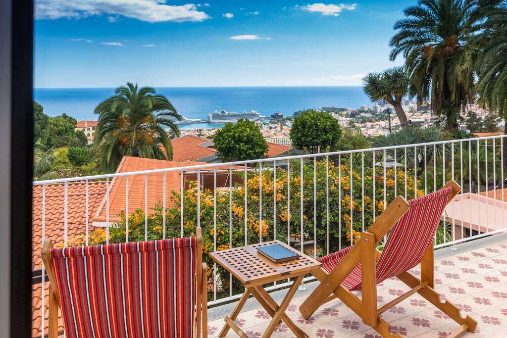 First floor balcony has 2 chairs, a parasol and a small table.