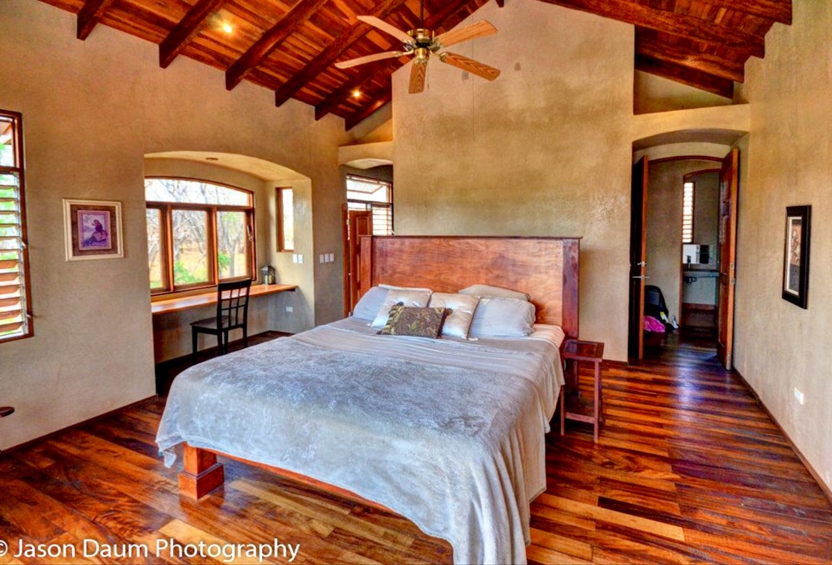 Chambre principale avec parquet et plafonds, lit king size en bois personnalisé et bureau