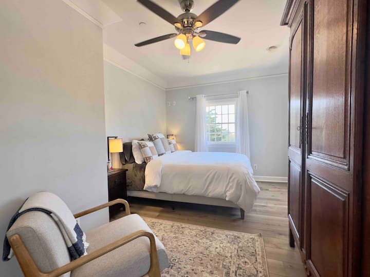 Dormitorio de invitados con una cama tamaño queen, amur para el almacenamiento y el área de estar. 