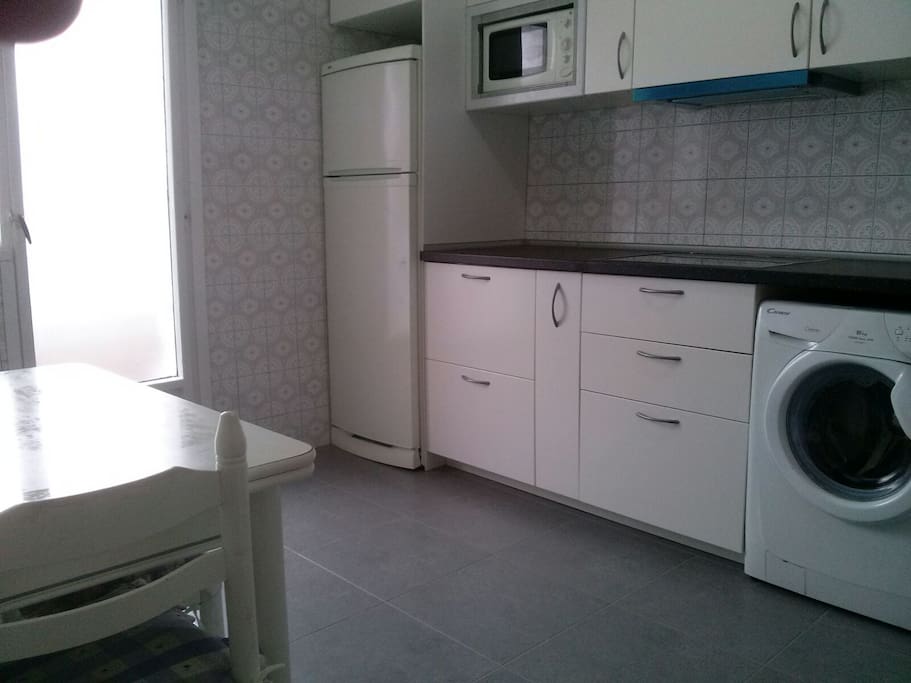 Cocina con ventana a terraza y plaza con jardin.