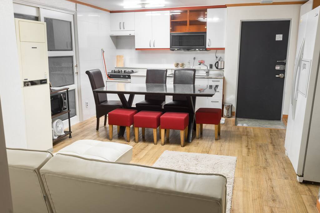 Living area with couch, big laptop friendly table, kitchen. The sliding door on the left has washer space. You can hang dry your towels on the rack there after shower. The couches fold down into beds if necessary. AC available as well.