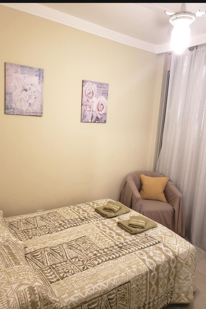 חדר שינה עם מיטה זוגית ומרפסת ברחוב. 