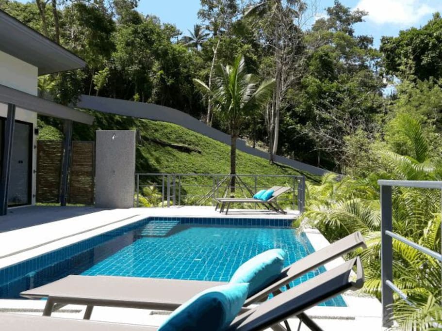 Swimming pool with sunbeds and terrace overlooking the tropical forest