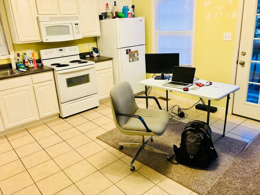 Kitchen area, makeshift computer work station, stove, oven and microwave, countertop space, opens to back deck.