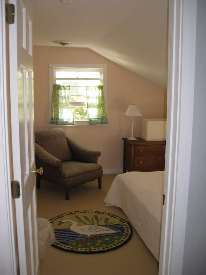 Cozy carpeted salmon colored bedroom with double-sized futon bed off wide spacious hallway. 