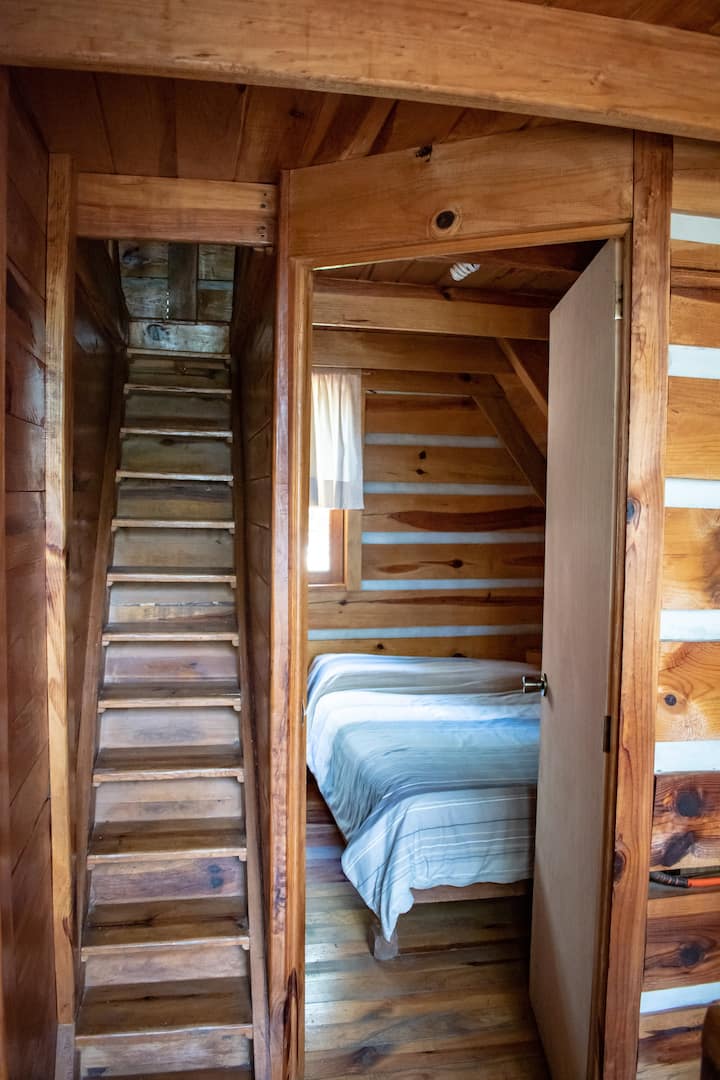 Izba s manželskou posteľou na prvom poschodí a schodmi do podkrovia 