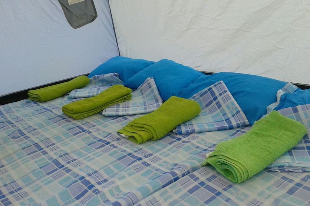 Tienda de campaña acondicionada con colchonetas y ropa de cama