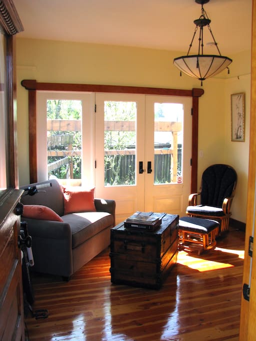 Living room from the front door with a view out the french doors to the garden on the south side. The loveseat does pull out to a bed if needed.