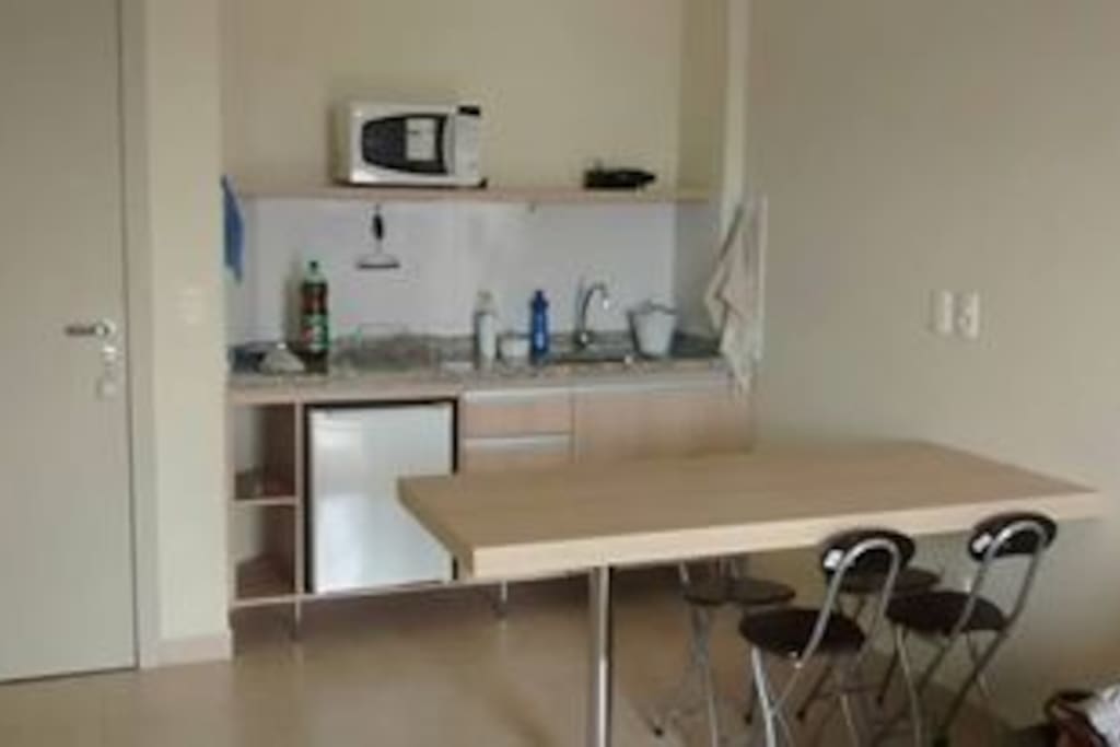Cozinha equipada com microondas, frigobar, pratos, copos e talheres.