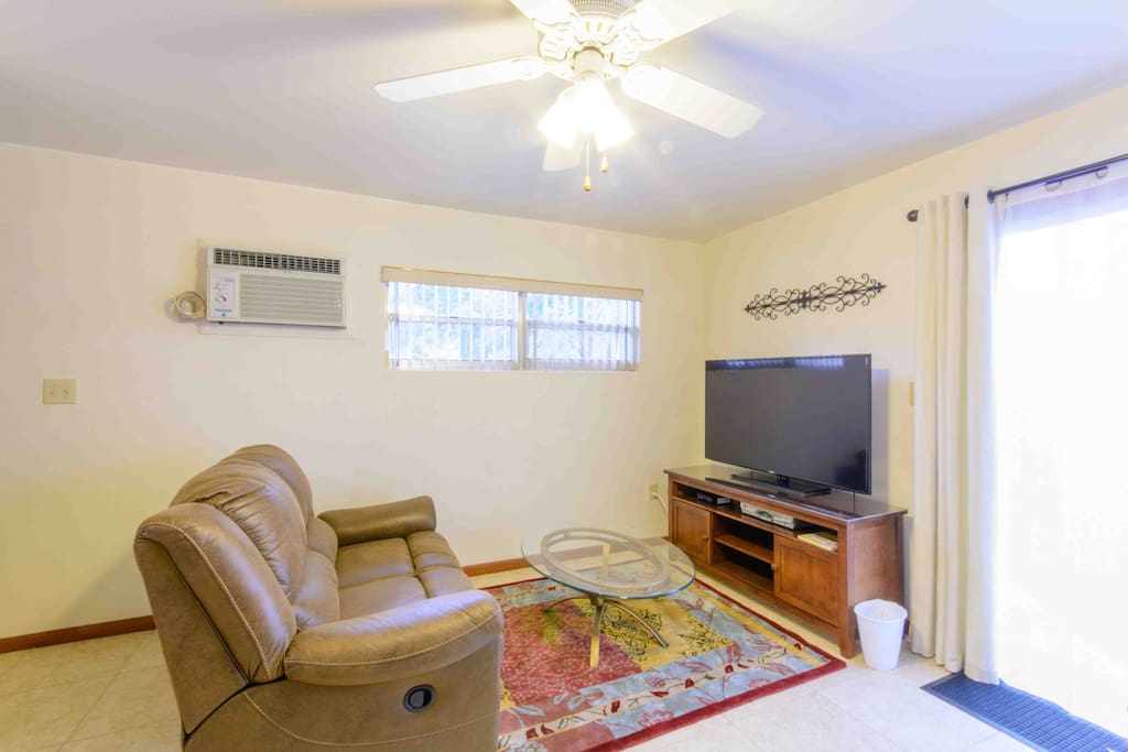 View of living room with large 55" TV, reclining love seat, coffee table and area rug.