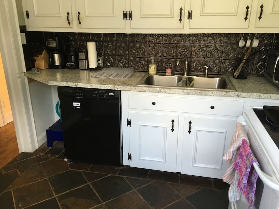 Kitchen has refrigerator, microwave, stove, oven and dishwasher, dishes, silverware, glasses, and mugs