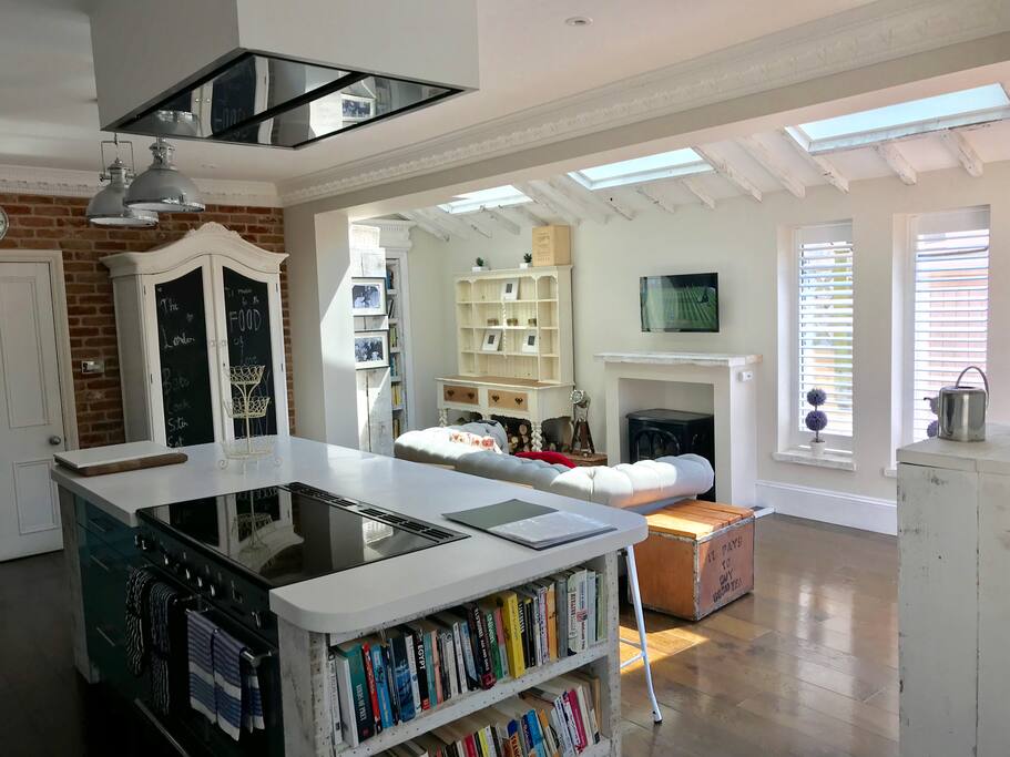 The large bright kitchen space with roof lights and the huge island with its induction range cooker set in the corian worktop.