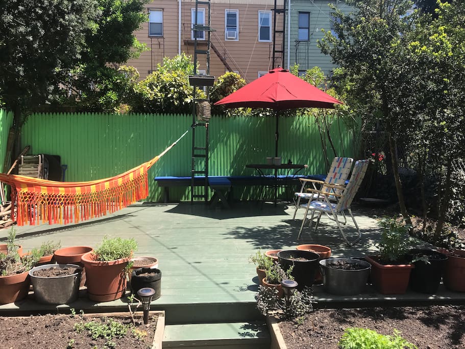 Private backyard with organic vegetable garden, hammocks, dining table & chairs & grill (updated w/ wood patio & benches)