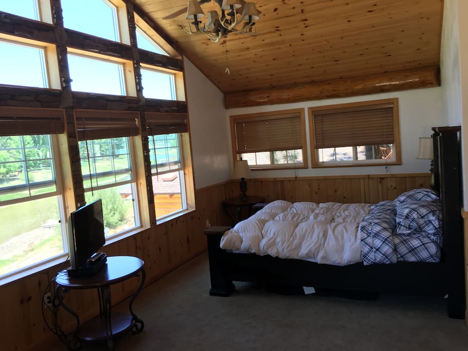 Main bedroom- queen with huge windows and custom fireplace and fan with view of lagoon and lake