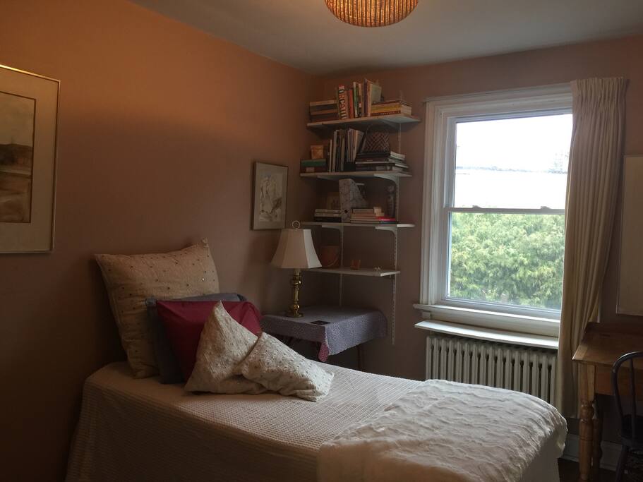 Twin-sized (small) bed with bedside lamp for curling up with a book.