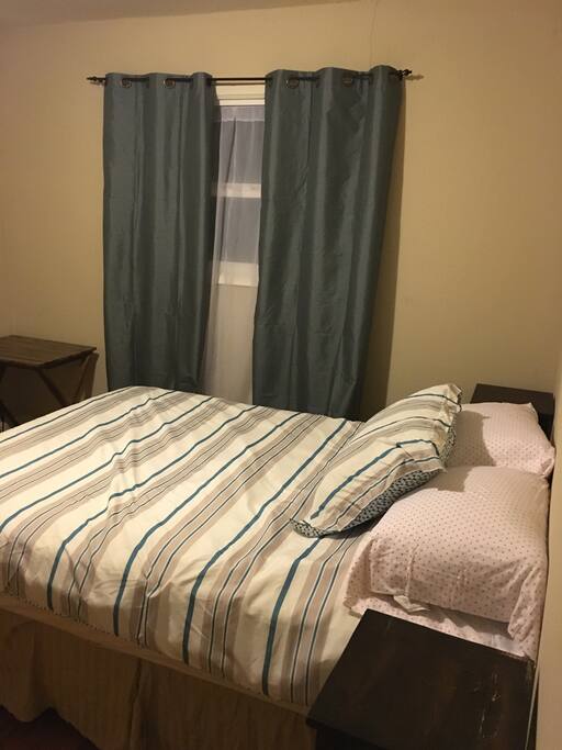 Another view of the room from the entrance. Can see desk and floor length blackout curtains.