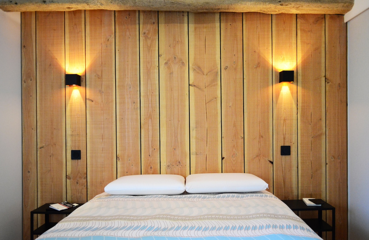 ห้องนอนใหญ่ที่มีคานเปิดโล่งและหัวเตียงไม้