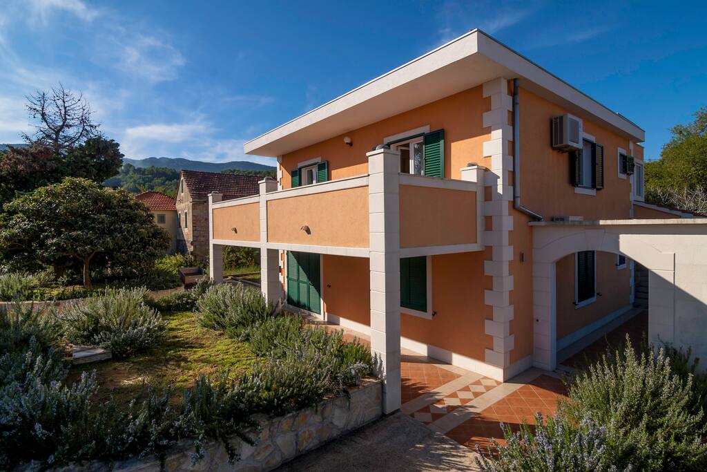 The entrance to the apartment is at the end of the passage on the right side of the house.