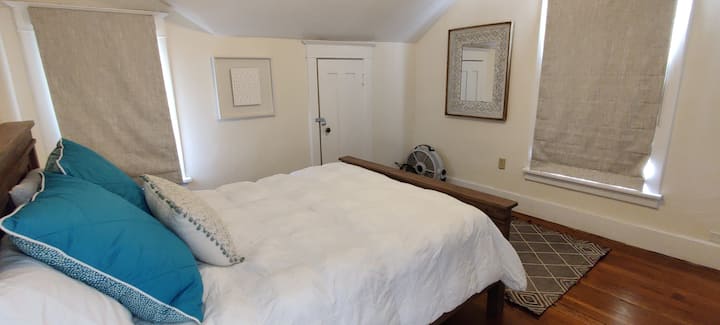 חדר שינה בקומה השנייה עם מזרן קווין ומצעים מסוגננים.